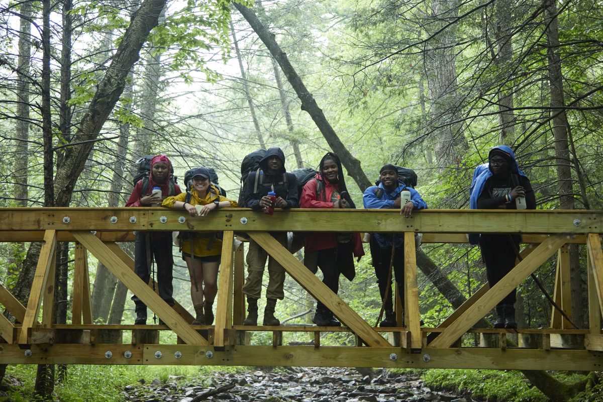 A group of ROTC cadets backpacking and posing on a bridge in the woods together. Photo by Justin Durner
