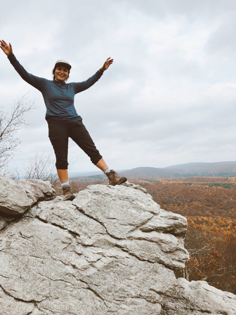 Maria with her hands in the air on top of a rock